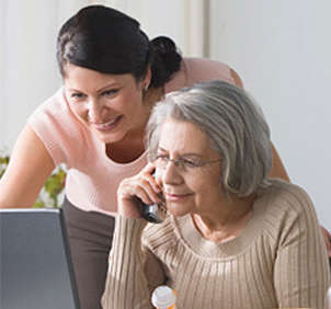 Woman helping older woman on her laptop