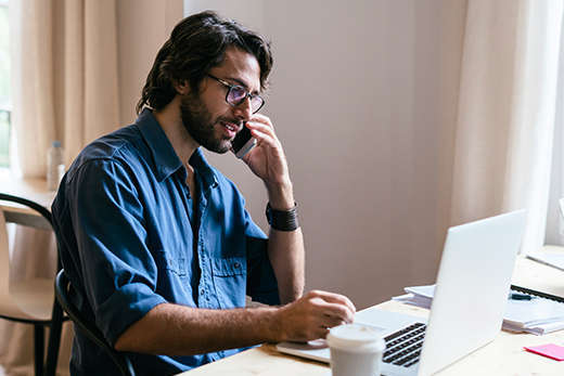 Bearded man with glasses working on laptop